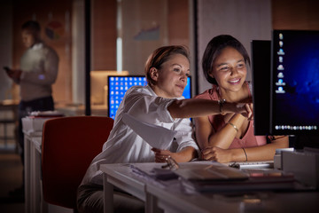 Female businesswomen working late at computer in dark office at night