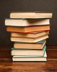 stack of colored books on old wooden shelf with dark background