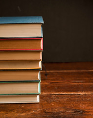 stack of multi-colored books on old wooden shelf with dark background
