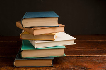stack of colored books on old wooden shelf with dark background