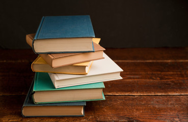 stack of colored books on old wooden shelf with dark background