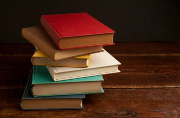 stack of colored books on old wooden shelf with dark background