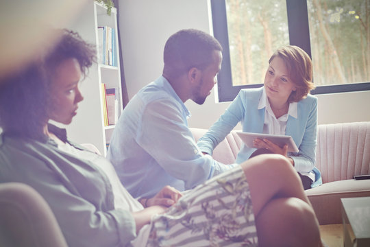 Female therapist digital tablet comforting man in couples therapy session