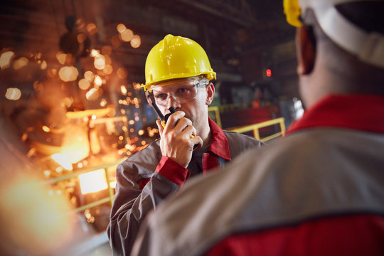 Steelworker talking, using walkie-talkie in steel mill
