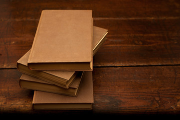 stack of old brown books on wooden table