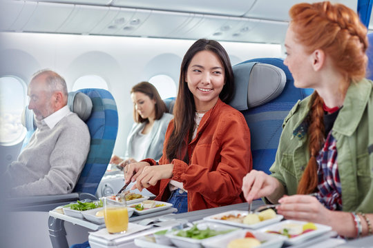 Women friends eating dinner and talking on airplane