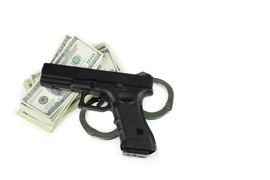 gun and metal handcuff on 100 dollars banknote stacking isolated on white background. crime concept
