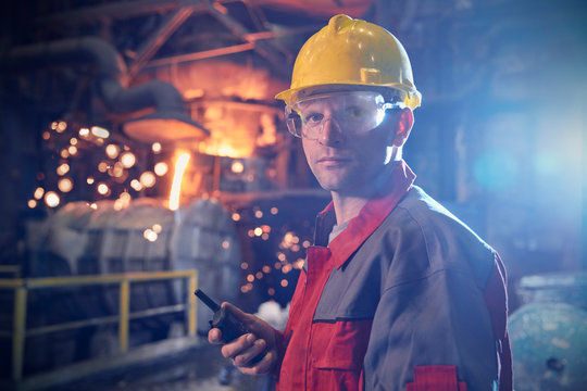 Portrait confident, serious steelworker walkie-talkie in steel mill