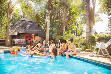 Young friends hanging out at tropical summer swimming pool