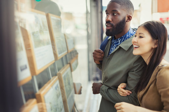 Young couple browsing real estate listings at storefront