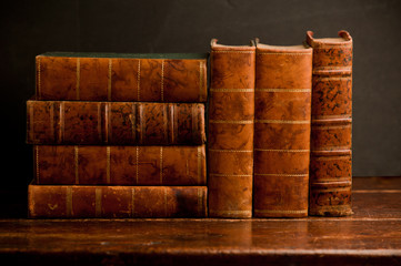 stack of old retro books on old wooden shelf and dark background