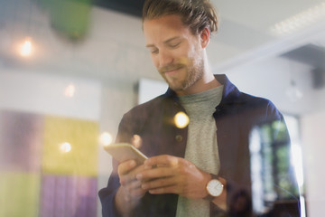 Smiling businessman texting with smart phone