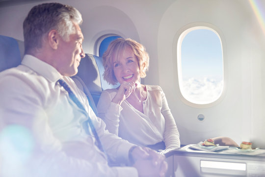 Smiling Mature Couple Eating And Talking In First Class On Airplane