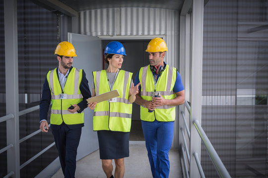 Supervisors with clipboard walking and talking on factory walkway