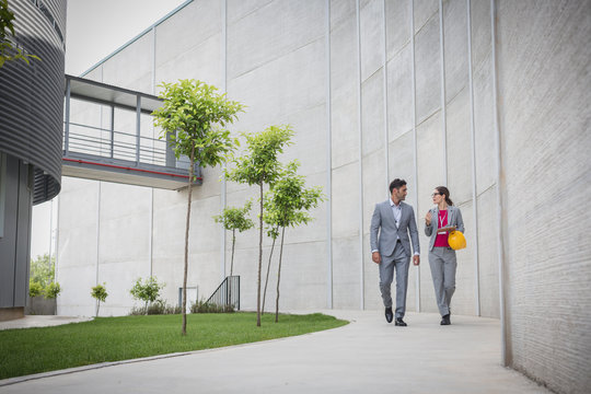 Supervisors walking on sidewalk outside factory
