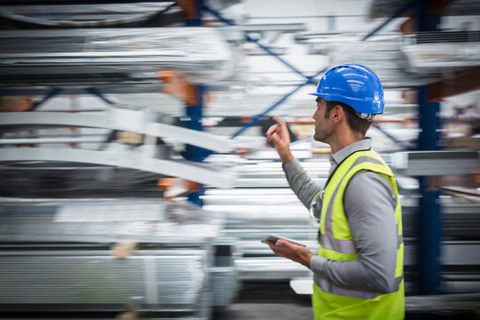 Male worker with digital tablet checking inventory in warehouse