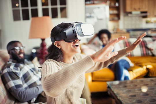 Woman gesturing, using virtual reality simulator glasses in living room