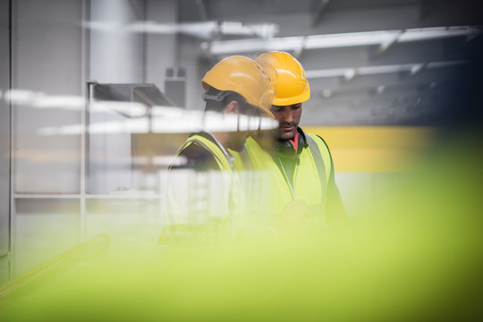 Male supervisors talking, looking down in factory