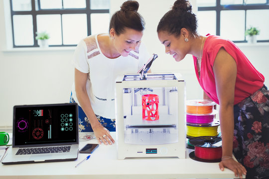 Female designers watching 3D printer in office
