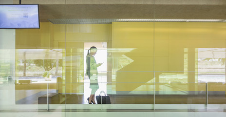 Silhouette businesswoman texting smart phone in modern office window
