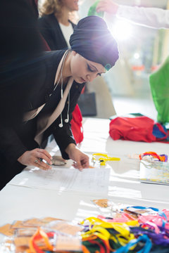 Businesswoman wearing headscarf checking in at conference registration table