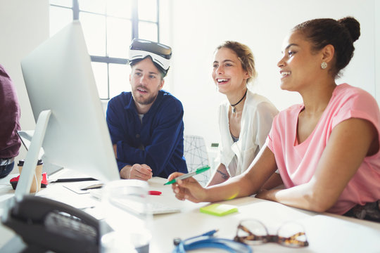 Computer programmers programming virtual reality simulator glasses at computer in office