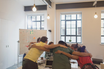 Designers bonding in huddle in conference room meeting