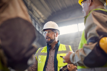 Supervisor talking to steelworkers in steel mill