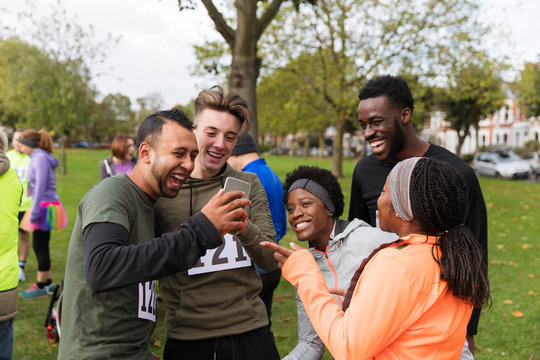 Friend runners with smart phone at charity run in park