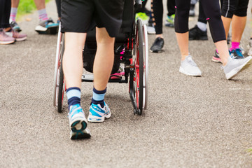 Man pushing wheelchair on crowded path