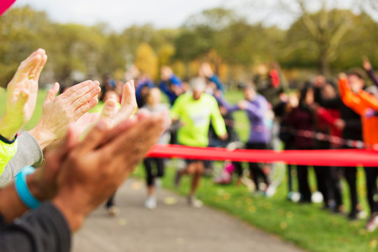 Spectators clapping for runners nearing finish line at charity event