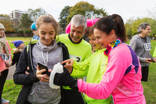 Family runners with smart phone at charity run in park