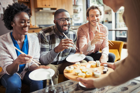 Friends eating sushi in living room