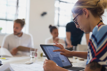 Female architect using touch screen laptop in conference room meeting