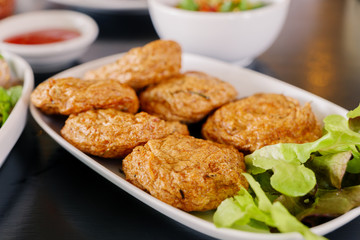 Thai Fried Fish Cake or Thai Deep fried fish pasty serve on white dish and black table.