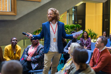 Smiling male speaker with microphone talking to conference audience