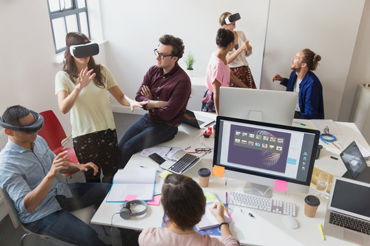 Computer programmers testing virtual reality simulator glasses in open plan office