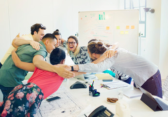 Enthusiastic architects bonding in huddle in conference room meeting