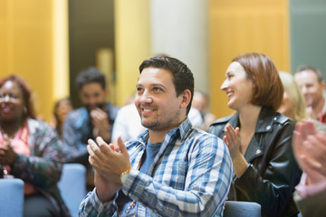 Smiling man clapping in conference audience