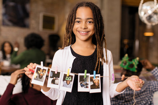 Portrait smiling girl holding string of instant photos