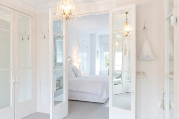 White, luxury home showcase interior bedroom French doors chandelier