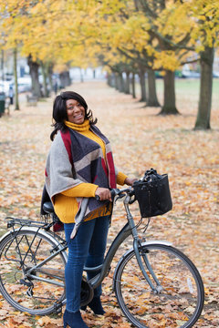 Portrait smiling, confident woman bike riding among trees and leaves in autumn park