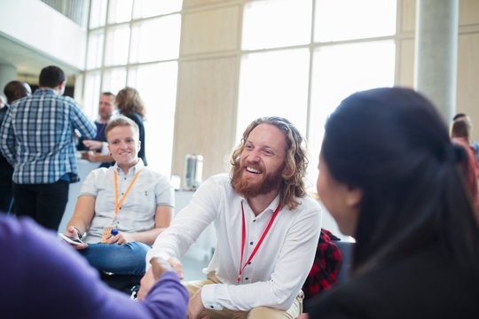 Smiling businessman shaking hands with colleague at conference