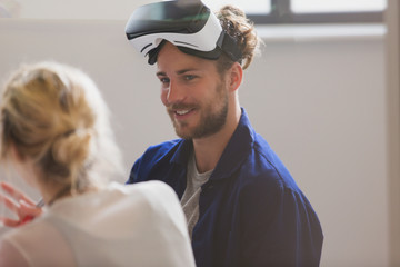 Smiling computer programmer wearing virtual reality simulator glasses