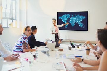 Female designer at television screen leading conference room meeting