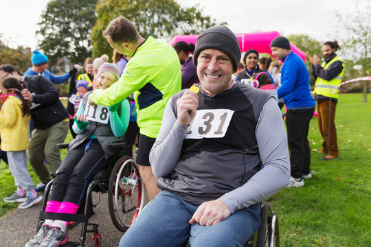 Portrait smiling, confident man in wheelchair showing medal at charity race in park