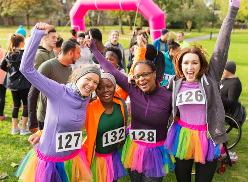 Portrait enthusiastic female runners in tutus cheering at charity run in park - Powered by Adobe
