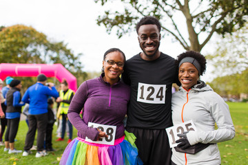 Portrait smiling, confident family marathon bibs at charity run in park