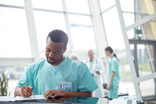 Male nurse reviewing medical record in hospital lobby