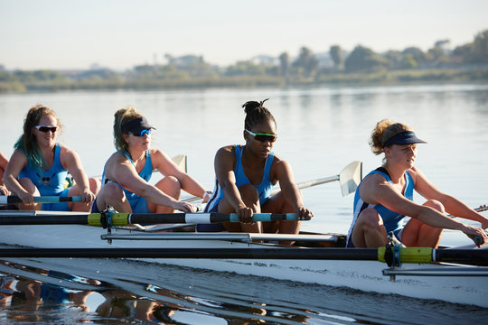 Female rowers rowing scull on sunny lake